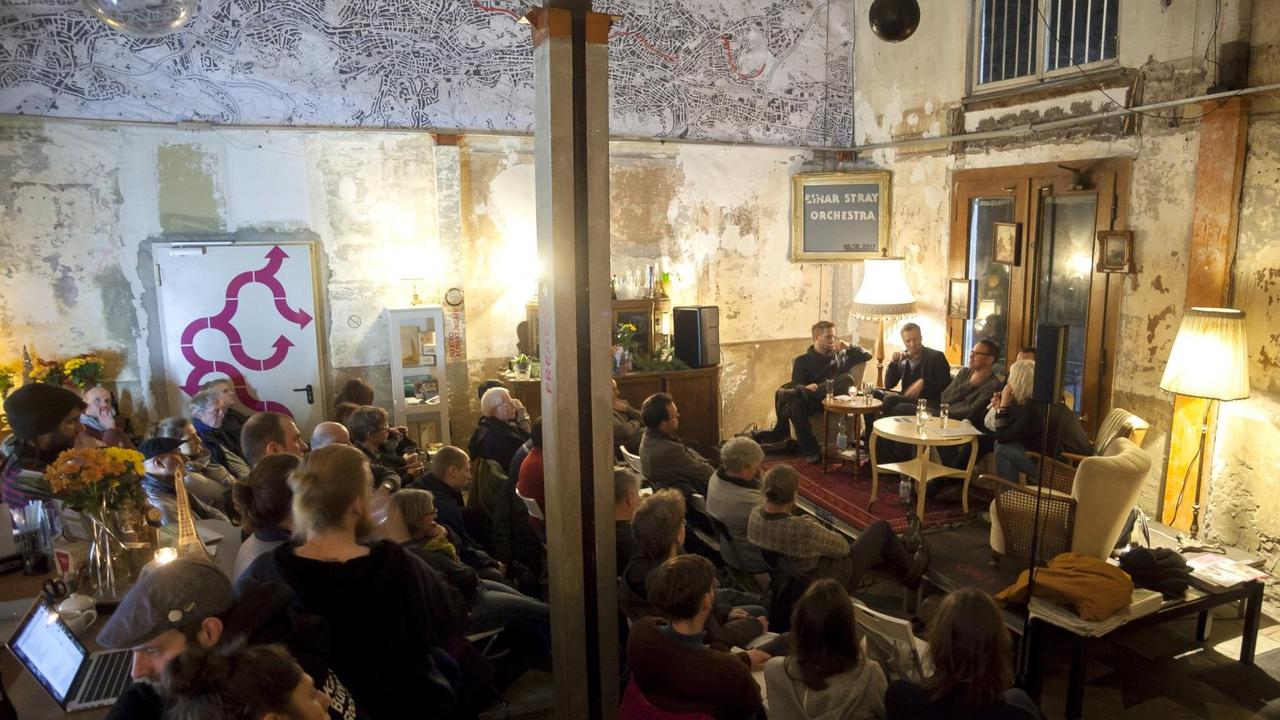 Zuhörerinnen und Zuhörer sitzen und lauschen einer Podiumsdiskussion. Zuhörerinnen und Zuhörer sitzen und lauschen einer Podiumsdiskussion.