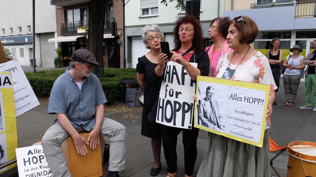 Angehörige von Colonia Dignidad-Opfern stehen mit Protest-Schildern in der Hand in Krefeld Angehörige von Colonia Dignidad-Opfern stehen mit Protest-Schildern in der Hand in Krefeld