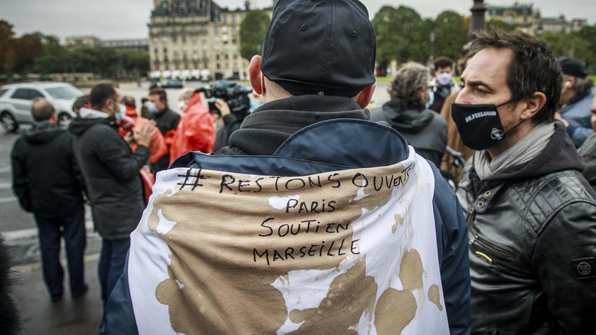 Ein Mann hat sich ein Spruchband mit der Aufschrift "Restons ouverts - Paris soutin Marseilles" umgehängt ("Bleiben wir offen - Paris unterstützt Marseille") Ein Mann hat sich ein Spruchband mit der Aufschrift "Restons ouverts - Paris soutin Marseilles" umgehängt ("Bleiben wir offen - Paris unterstützt Marseille")