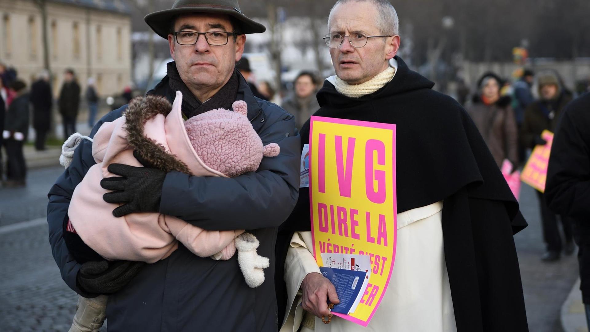 Ein Priester und ein Mann mit Kind auf dem Arm demonstrieren im Januar in Paris gegen Abtreibungen