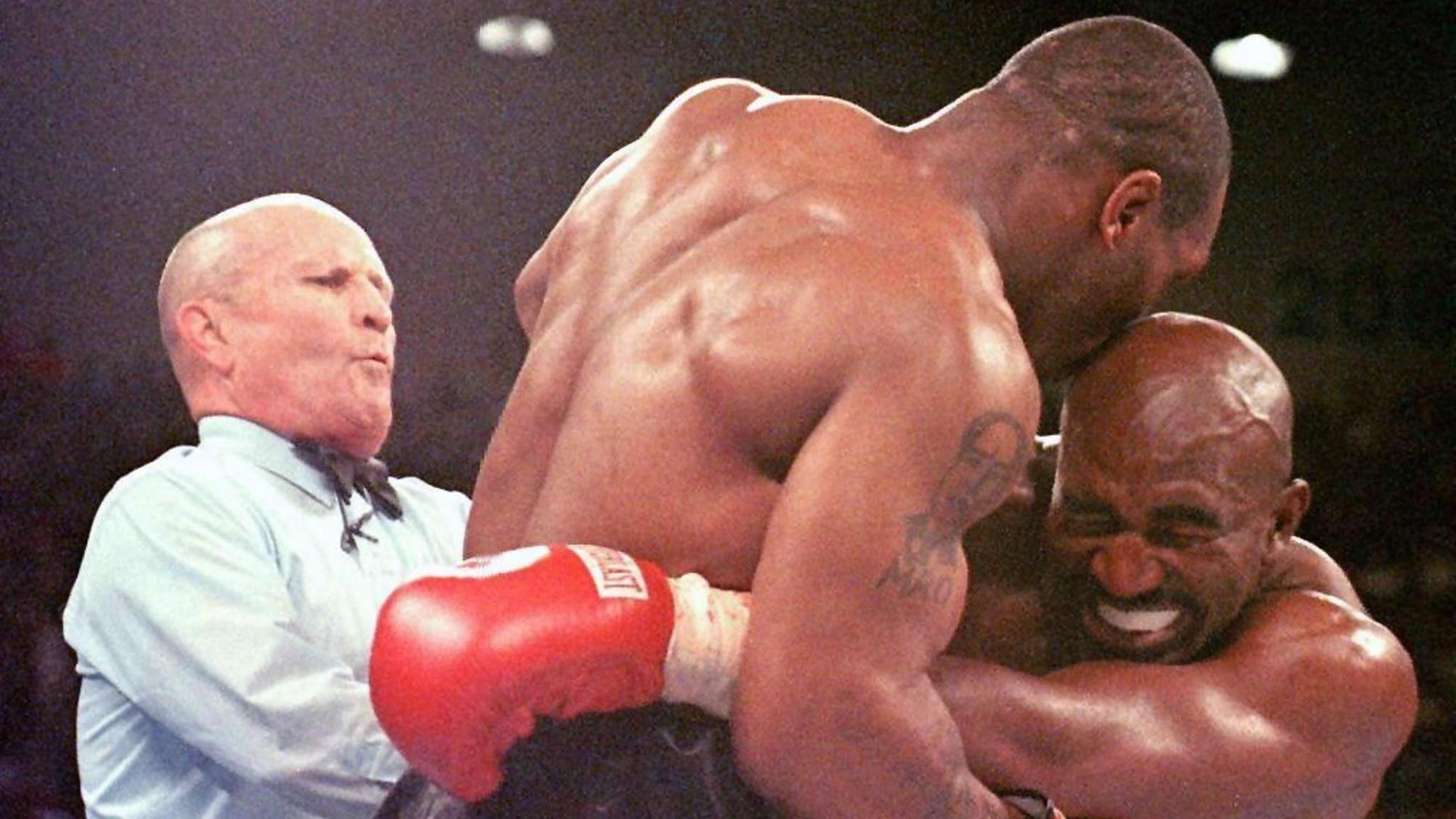 Der Weltmeister im Schwergewicht, Evander Holyfield (r), verzieht am 28.06.1997 in Las Vegas das Gesicht, nachdem ihn sein Herausforderer Mike Tyson (M) ins Ohr gebissen hat. Ringrichter Lane Mills (l) unterbricht in diesem Moment den Kampf. Tyson wurde nach der dritten Runde disqualifiziert. Nach nur dreistündiger Anhörung entschied Nevadas Sport-Kommission am Montag (19.10.1998) in Las Vegas mit 4:1- Stimmen, dem ehemaligen Schwergewichts-Weltmeister seine daraufhin vor einem Jahr entzogene Box-Lizenz zurückzugeben. Der Weltmeister im Schwergewicht, Evander Holyfield (r), verzieht am 28.06.1997 in Las Vegas das Gesicht, nachdem ihn sein Herausforderer Mike Tyson (M) ins Ohr gebissen hat. Ringrichter Lane Mills (l) unterbricht in diesem Moment den Kampf. Tyson wurde nach der dritten Runde disqualifiziert. Nach nur dreistündiger Anhörung entschied Nevadas Sport-Kommission am Montag (19.10.1998) in Las Vegas mit 4:1- Stimmen, dem ehemaligen Schwergewichts-Weltmeister seine daraufhin vor einem Jahr entzogene Box-Lizenz zurückzugeben.