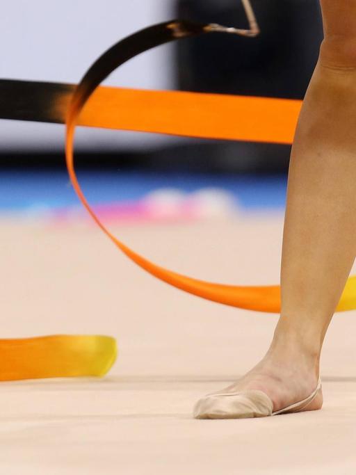 Ein Fuß in einem Gymnastikschuh neben einem Gymnastikband