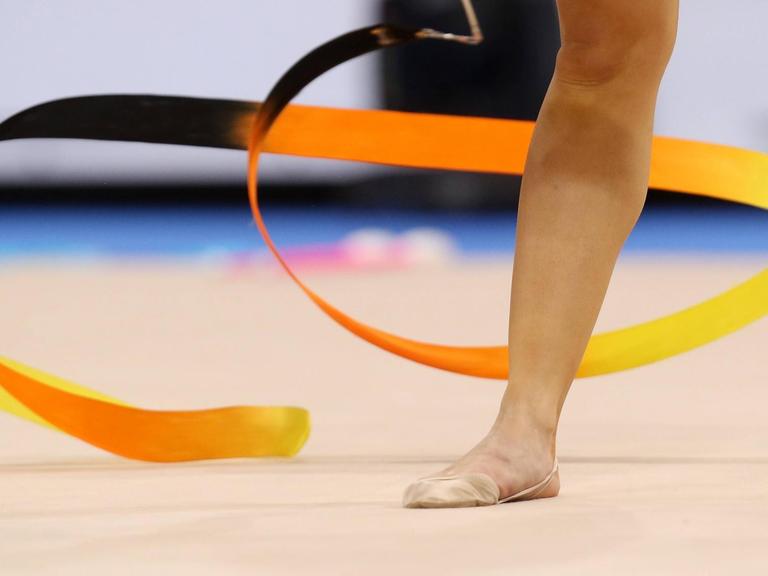 Ein Fuß in einem Gymnastikschuh neben einem Gymnastikband