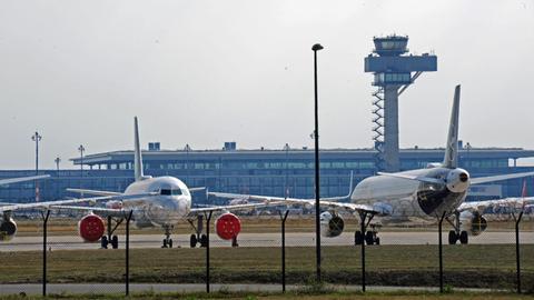 Lufthansa Maschinen parken auf dem Gelände des noch nicht eroeffneten Flughafens BER - im Hintergrund sind Terminal und Tower erkennbar.