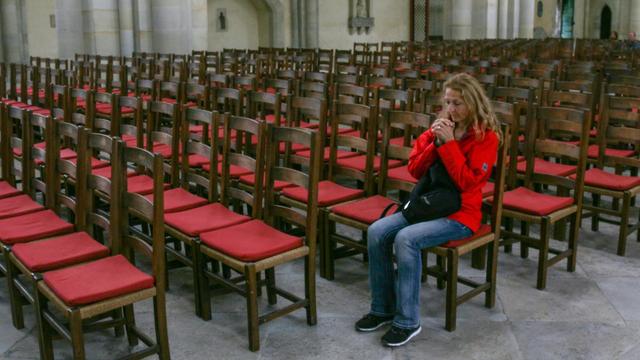 Frau sitzt im Magdeburger Dom inmitten leerer Stuhlreihen und betet.