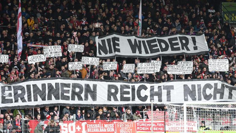 Schwarzwaldstadion: Zuschauer halten Plakate mit der Aufschrift "Nie wieder! Erinnern reicht nicht" in die Höhe.