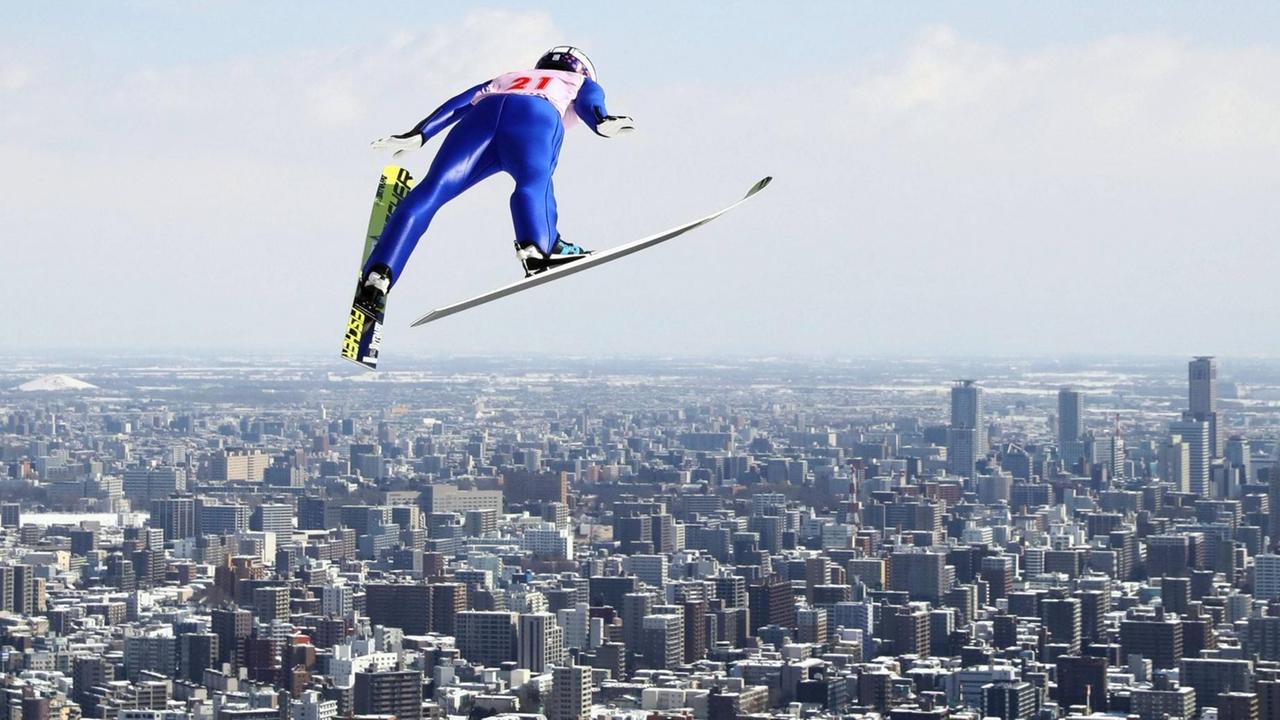 Diesen Blick wird es bei den Winderspielen 2026 nicht geben: Skisprung über den Hochhäusern der japanischen Stadt Sapporo. Diesen Blick wird es bei den Winderspielen 2026 nicht geben: Skisprung über den Hochhäusern der japanischen Stadt Sapporo.