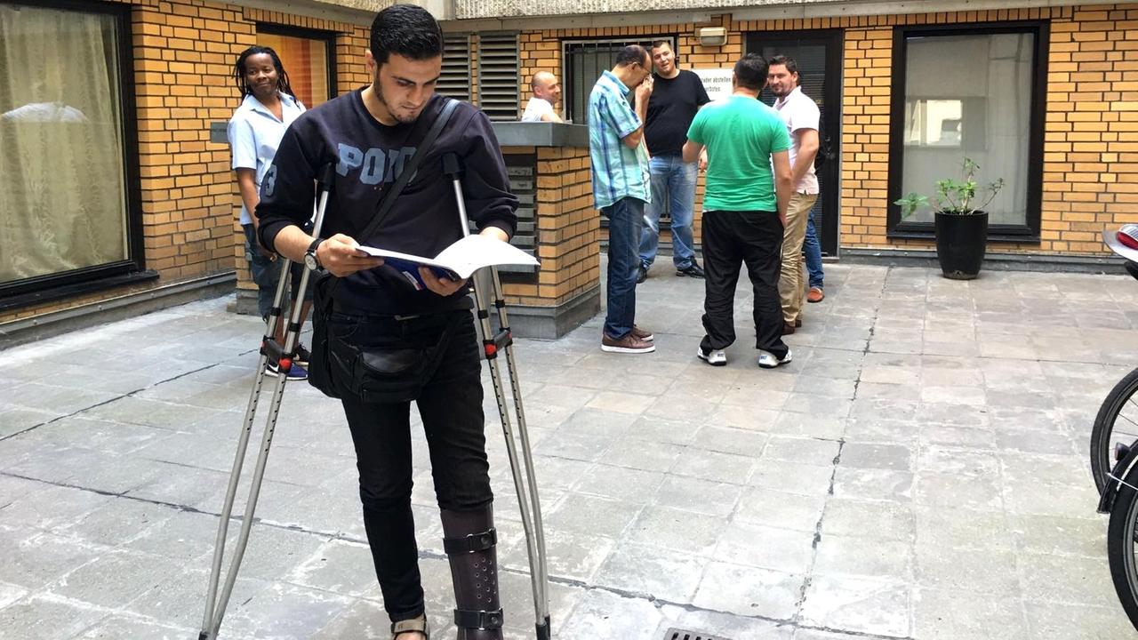 Der Syrer Karim steht auf Krücken gestützt im Innenhof der Berliner Sprachschule