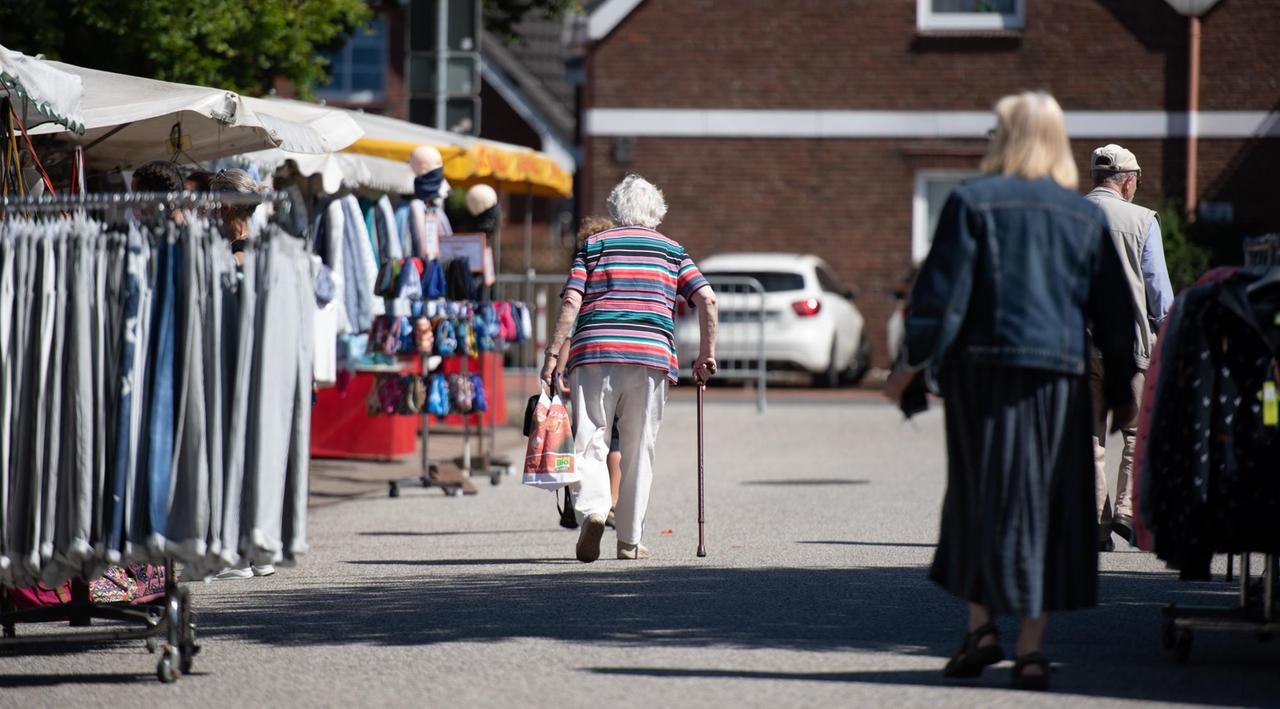 Eine ältere Frau geht über den Wochenmarkt.