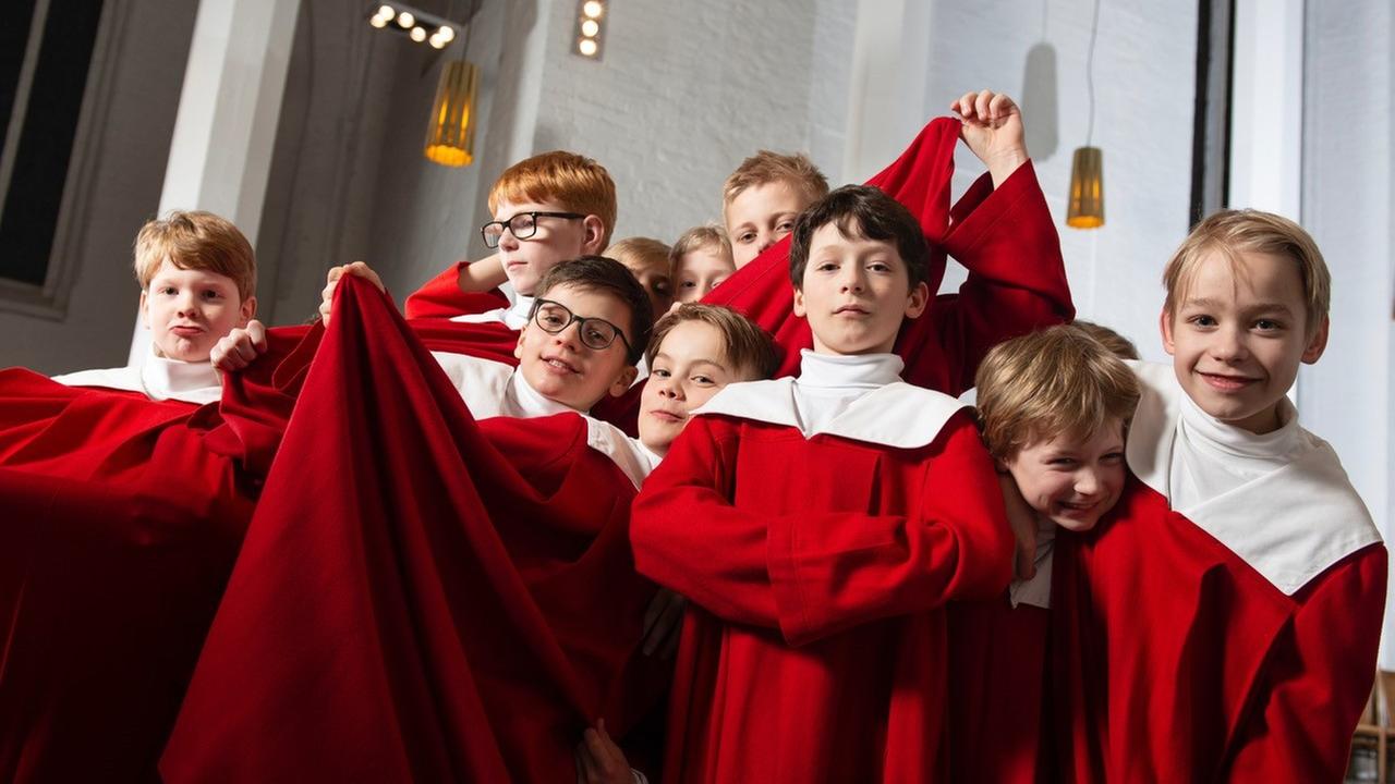 Jungs in roter und weißer Chorkleidung lachen und albern herum. Jungs in roter und weißer Chorkleidung lachen und albern herum.