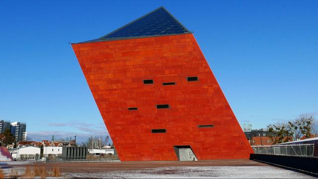 Das Museum des Zweiten Weltkriegs Danzig, ein vierseitiger Kubus, der schräg aus dem Boden ragt. Das Bauwerk wurde vom Architekturbüro Kwadrat entworfen.
