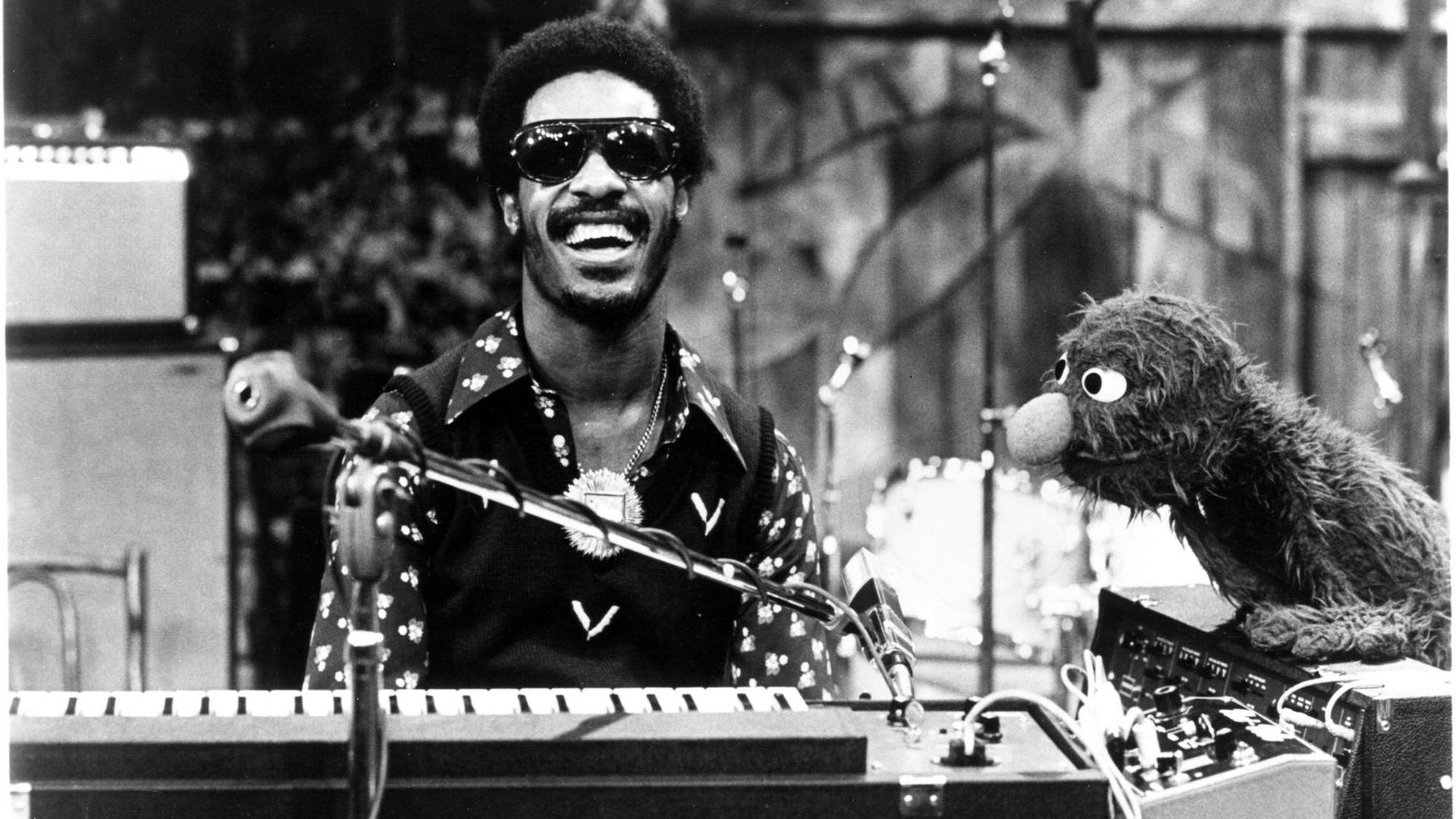 Der Musiker Stevie Wonder sitzt in der US-Kindersendung "Sesamstraße" lachend am Keyboard, neben ihm die Figur Grobi. Der Musiker Stevie Wonder sitzt in der US-Kindersendung "Sesamstraße" lachend am Keyboard, neben ihm die Figur Grobi.