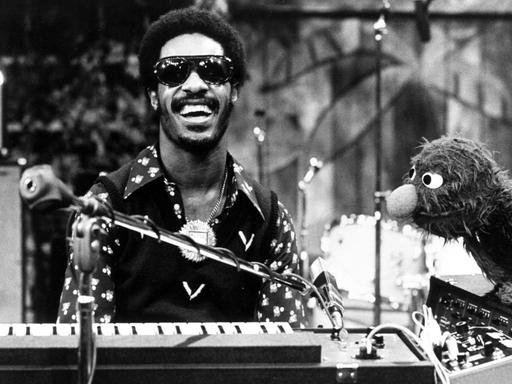 Der Musiker Stevie Wonder sitzt in der US-Kindersendung "Sesamstraße" lachend am Keyboard, neben ihm die Figur Grobi.