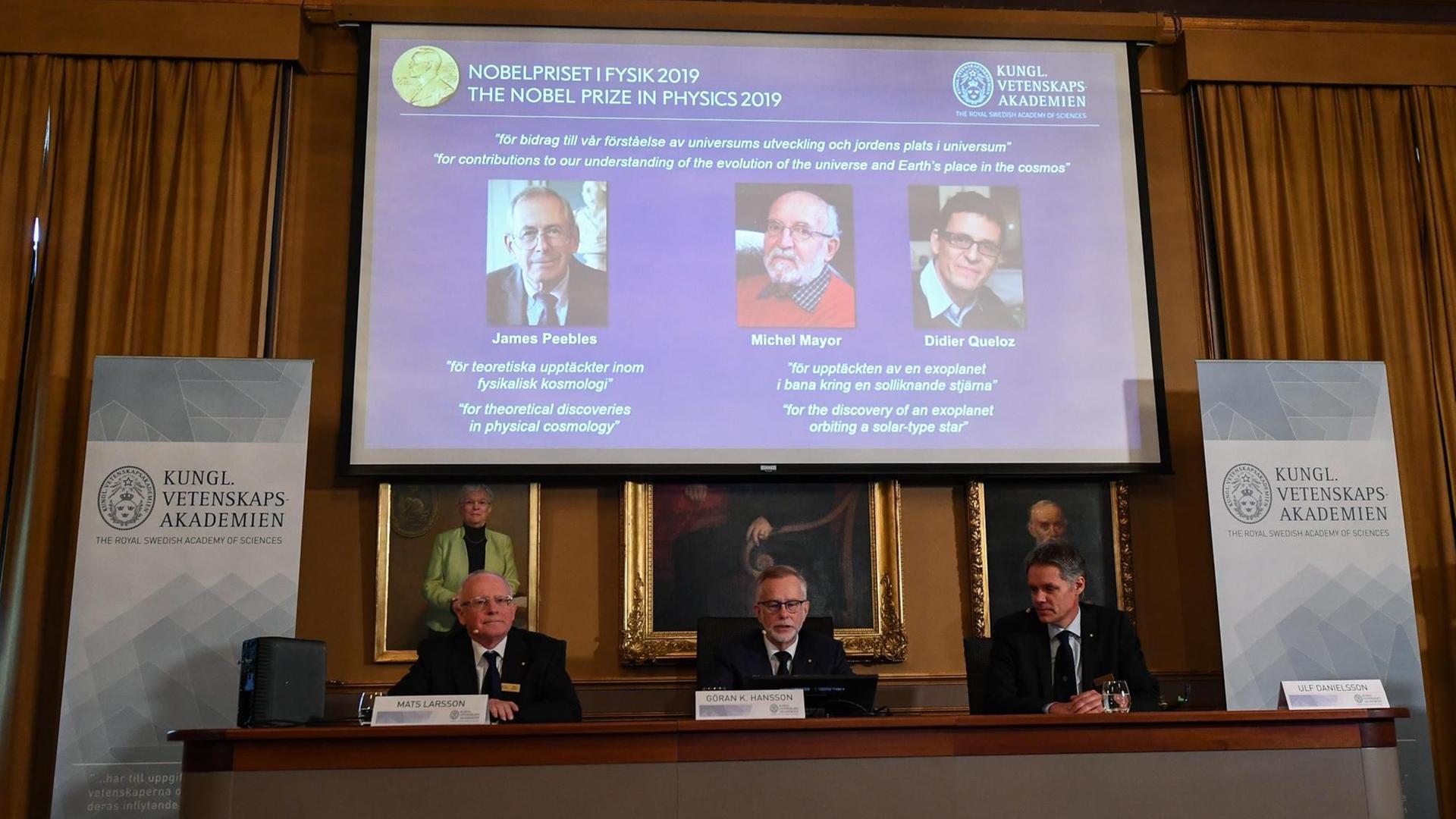 Bekanntgabe der Preisträger in Stockholm. Auf einem Podium sitzen Mitglieder der Schwedischen Akademie der Wissenschaften. Hinter ihnen auf einem Bildschirm sind die Fotos der Preisträger eingeblendet. Bekanntgabe der Preisträger in Stockholm. Auf einem Podium sitzen Mitglieder der Schwedischen Akademie der Wissenschaften. Hinter ihnen auf einem Bildschirm sind die Fotos der Preisträger eingeblendet.
