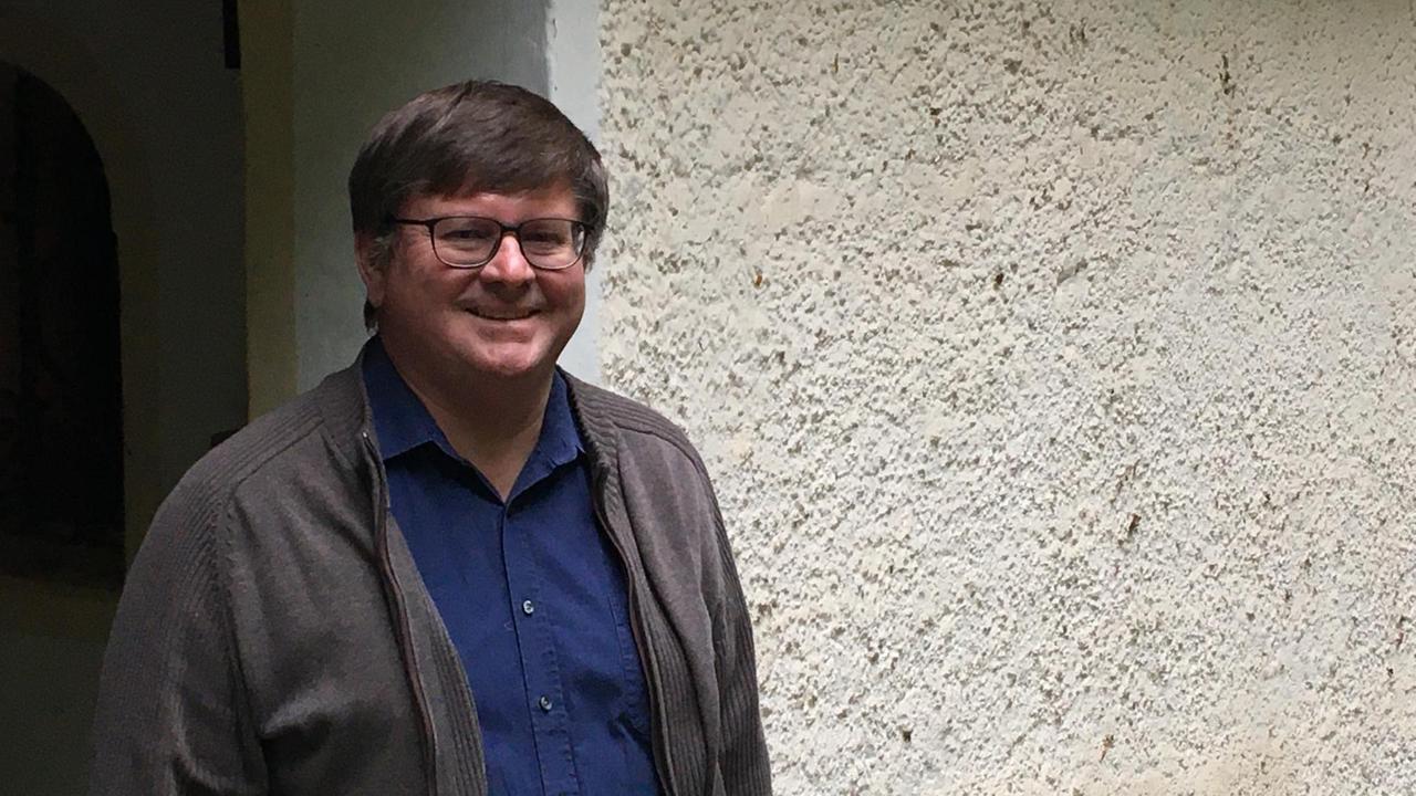 Der Pfarrer Josef Steinberger blickt freundlich aus dem Eingang der St. Corona-Kapelle im bayerischen Sauerlach-Arget Der Pfarrer Josef Steinberger blickt freundlich aus dem Eingang der St. Corona-Kapelle im bayerischen Sauerlach-Arget