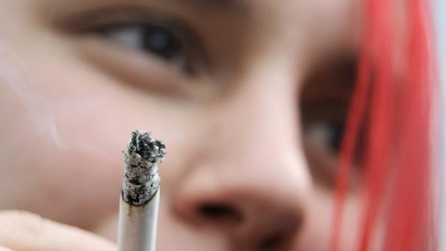 Eine junge Frau raucht eine Zigarette in München
