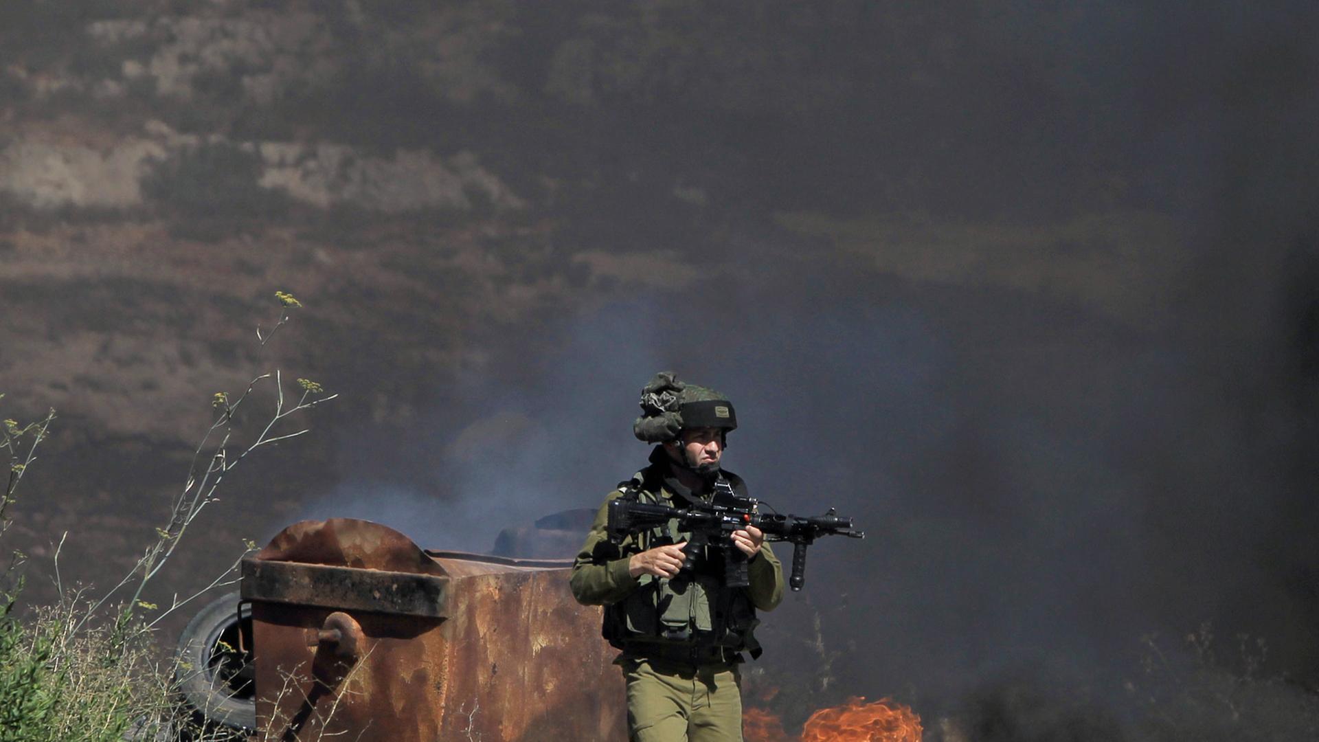 Ein bewaffneter israelischer Soldat steht neben brennenden Reifen während Auseinandersetzungen mit Palästinensern nahe einer jüdischen Siedlung bei Ramallah.