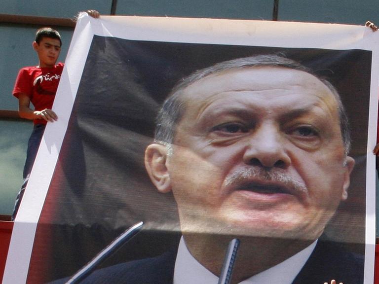 Zwei jungen halten ein Plakat von Erdogan hoch.