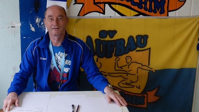 Andreas Steinhoff sitzt an einem Tisch, an der Wand hinter ihm hängt ein Banner seines Vereins Andreas Steinhoff sitzt an einem Tisch, an der Wand hinter ihm hängt ein Banner seines Vereins