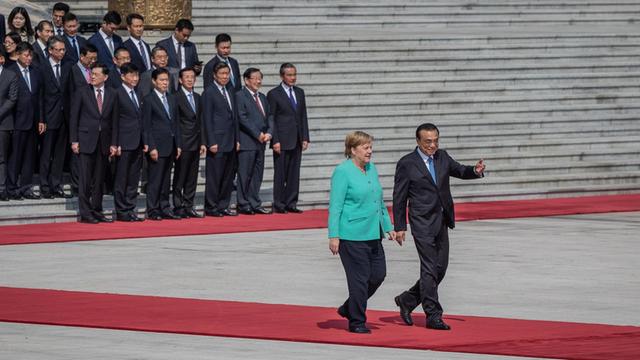 Chinas Premier Li Keqiang (re.) und Bundeskanzlerin Angela Merkel (li.) schreiten gemeinsam auf dem roten Teppich vor der Großen Halle in Peking.