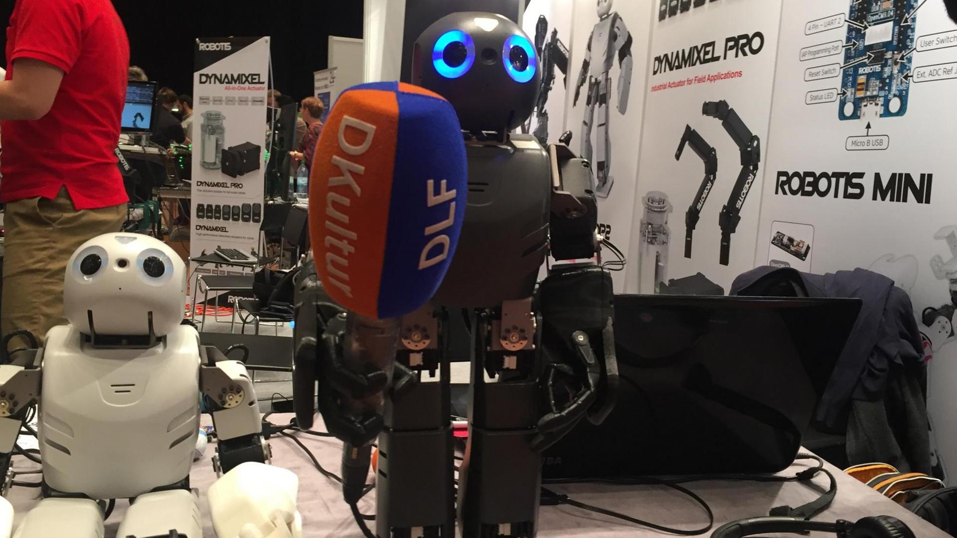 Zwei Roboter, fotografiert auf der Roboter Messe Hamburg. Einer hält ein Mikrofon in der Hand. Zwei Roboter, fotografiert auf der Roboter Messe Hamburg. Einer hält ein Mikrofon in der Hand.