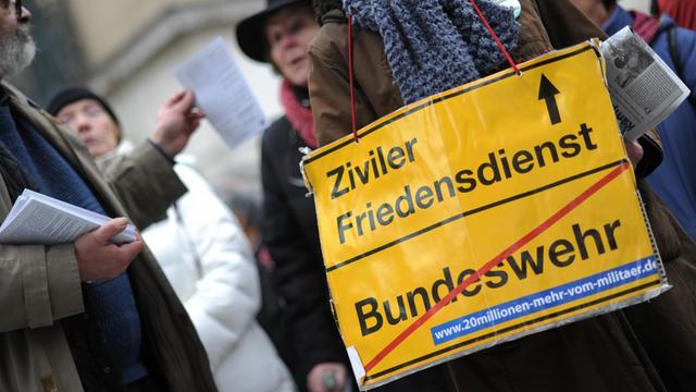 Eine Teilnehmerin einer Kundgebung anlässlich des Ostermarsches in München (Bayern) am 30.03.2013 mit einem Plakat, auf dem die Abschaffung der Bundeswehr zugunsten eines zivilen Friedensdienstes gefordert wird.