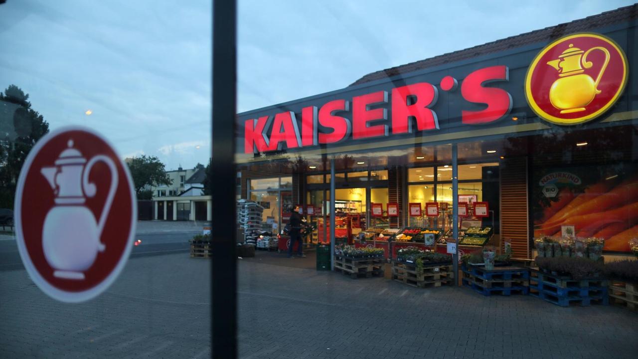 Ein roter Kaiser's-Schriftzug leuchtet am Abend an dem Markt. Ein roter Kaiser's-Schriftzug leuchtet am Abend an dem Markt.