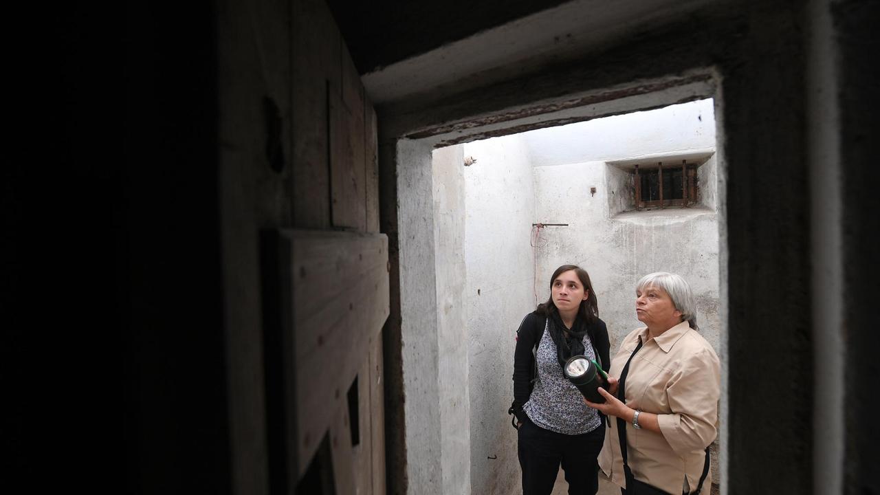 In einer Arrestzelle des ehemaligen KZ Sachsenburg in Frankenberg (Sachsen) leuchten Gisela Heiden (r.) und Anna Schüller mit einer Taschenlampe auf Inschriften an der Wand. In einer Arrestzelle des ehemaligen KZ Sachsenburg in Frankenberg (Sachsen) leuchten Gisela Heiden (r.) und Anna Schüller mit einer Taschenlampe auf Inschriften an der Wand.