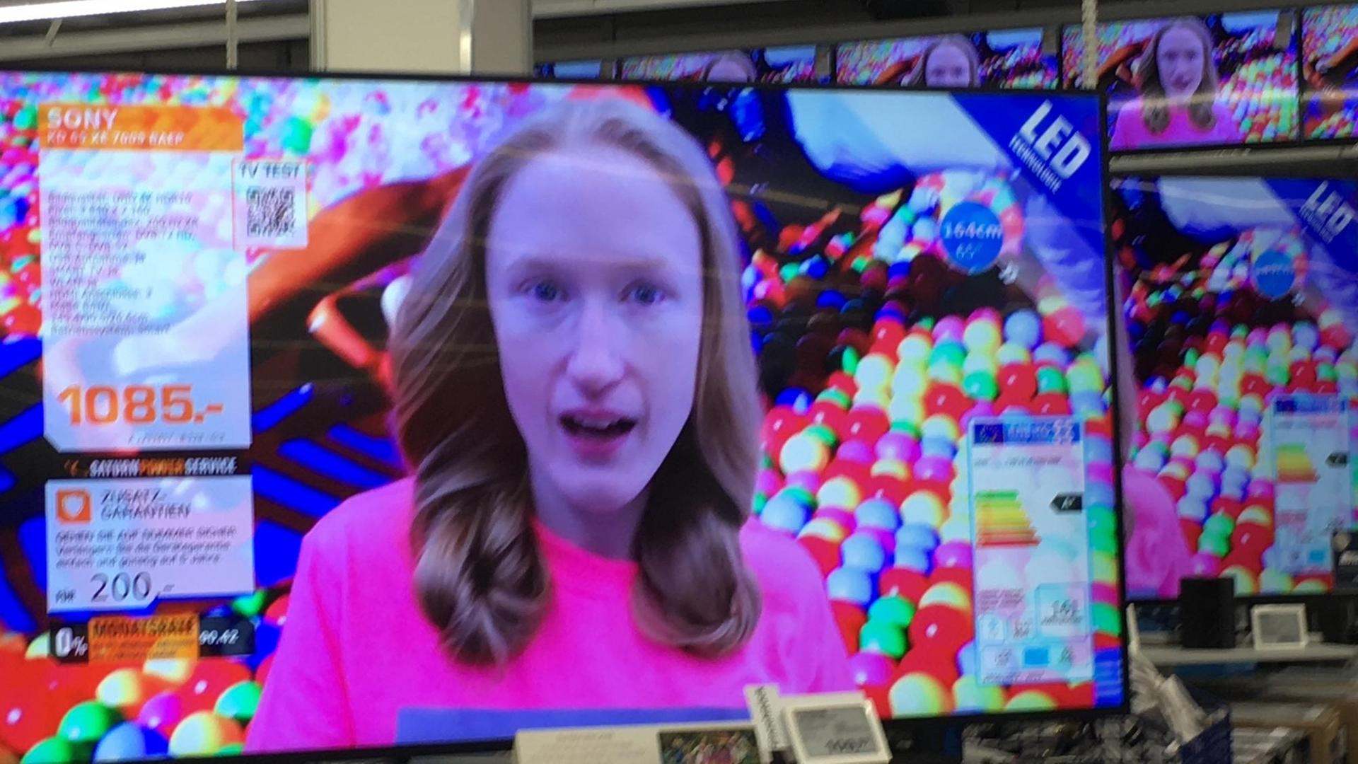 Das Gesicht der Künstlerin Britta Thie ist auf einem Flachbildschirm-Fernseher zu sehen, der in einem Elektrofachhandel steht Das Gesicht der Künstlerin Britta Thie ist auf einem Flachbildschirm-Fernseher zu sehen, der in einem Elektrofachhandel steht