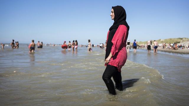 Eine junge Frau geht am französischen Strand 'Fort-Mahon' im Burkini ins Meer.