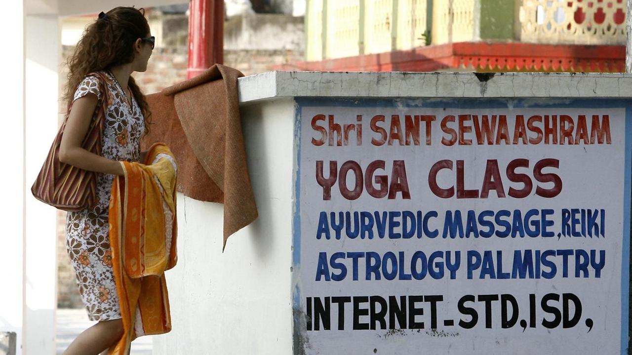 Touristen vor einer Inschrift, die für Yoga-Kurse wirbt, im indischen Rishikesh. Touristen vor einer Inschrift, die für Yoga-Kurse wirbt, im indischen Rishikesh.