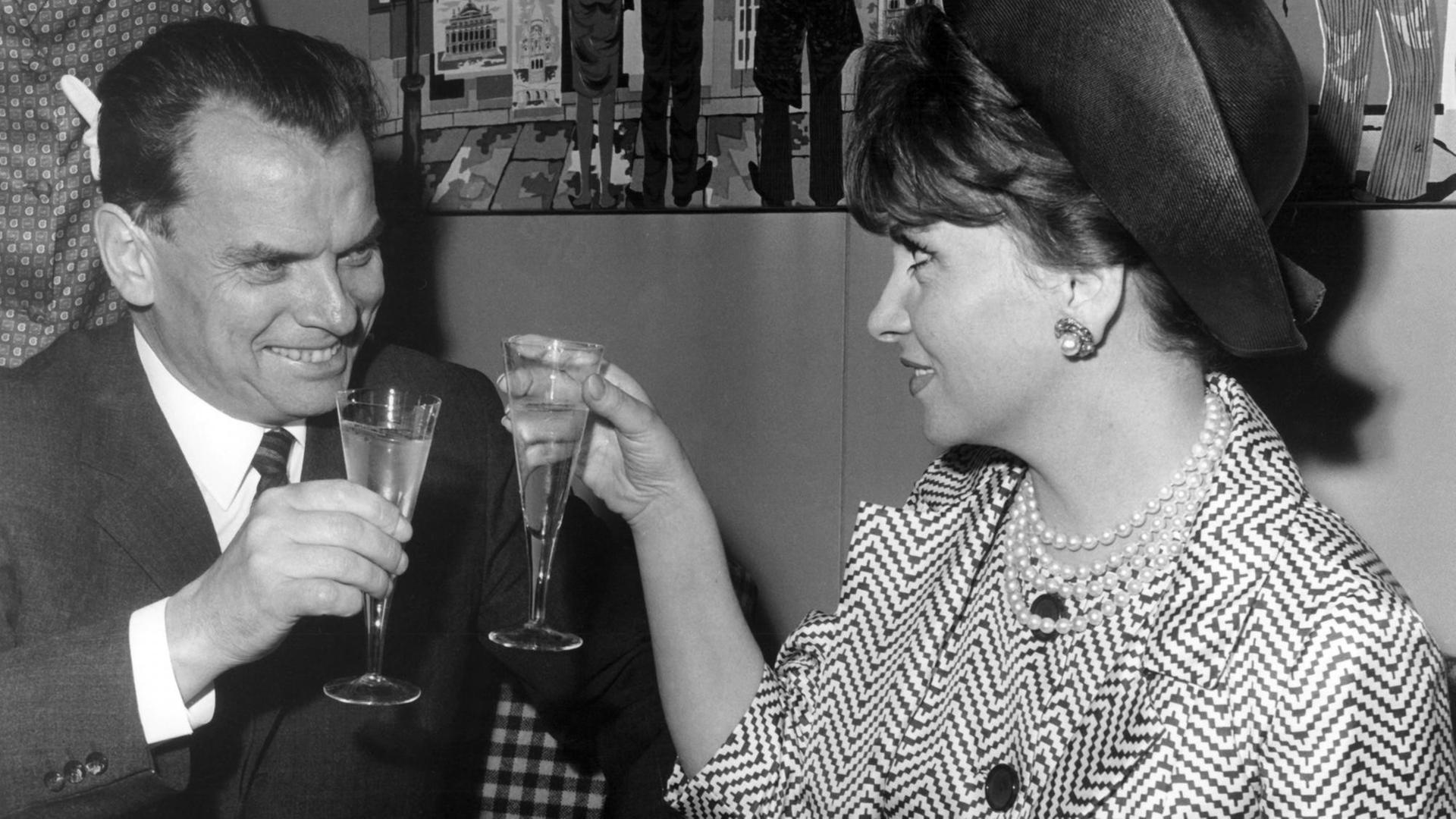 Der Berlinale-Festspielleiter Afred Bauer begrüßt die italienische Schauspielerin Gina Lollobrigida nach ihrer Ankunft auf dem Flughafen Tegel in Berlin am 02.07.1965 mit einem Glas Sekt Der Berlinale-Festspielleiter Afred Bauer begrüßt die italienische Schauspielerin Gina Lollobrigida nach ihrer Ankunft auf dem Flughafen Tegel in Berlin am 02.07.1965 mit einem Glas Sekt