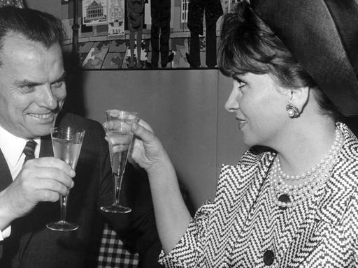 Der Berlinale-Festspielleiter Afred Bauer begrüßt die italienische Schauspielerin Gina Lollobrigida nach ihrer Ankunft auf dem Flughafen Tegel in Berlin am 02.07.1965 mit einem Glas Sekt