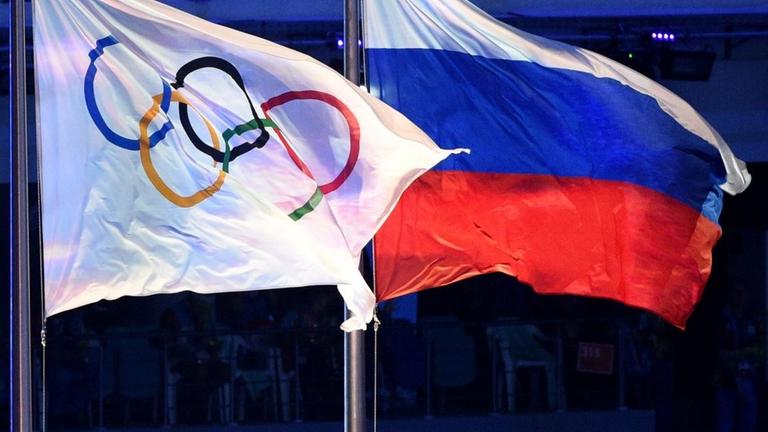 Das Foto zeigt die olympische und die russische Flagge.