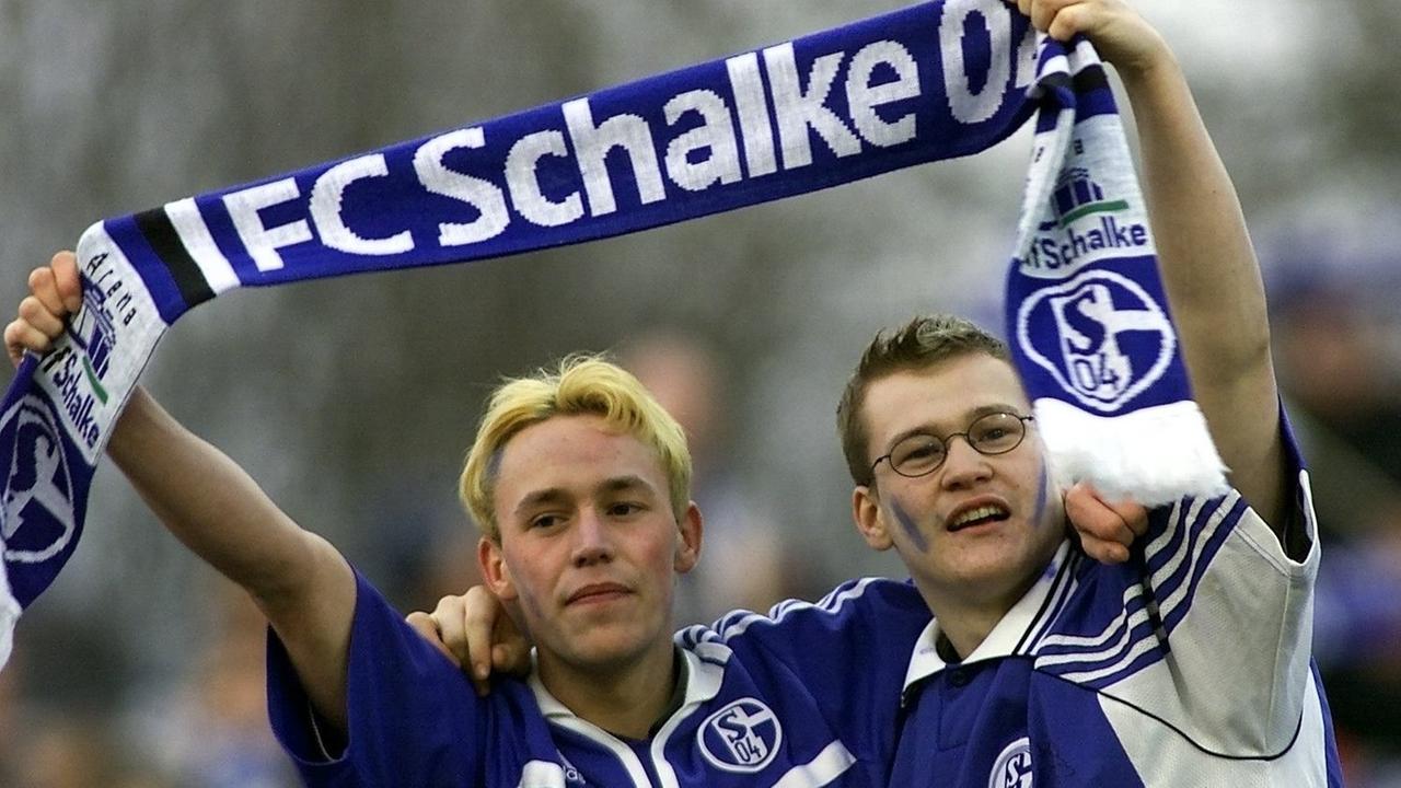 Zwei Schalke-Fußballfans feiern mit erhobenem Vereinsschal. Der FC Schalke 04 gewinnt am 10.02.2001 im Gelsenkirchener Parkstadion das Fußball-Bundesligaspiel der 21. Runde gegen den TSV 1860 München mit 2:0. | Verwendung weltweit