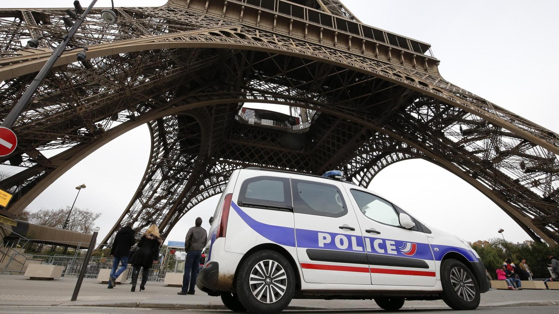 Ein Polizeiauto passiert in Frankreich den Eiffel-Turm. Ein Polizeiauto passiert in Frankreich den Eiffel-Turm.