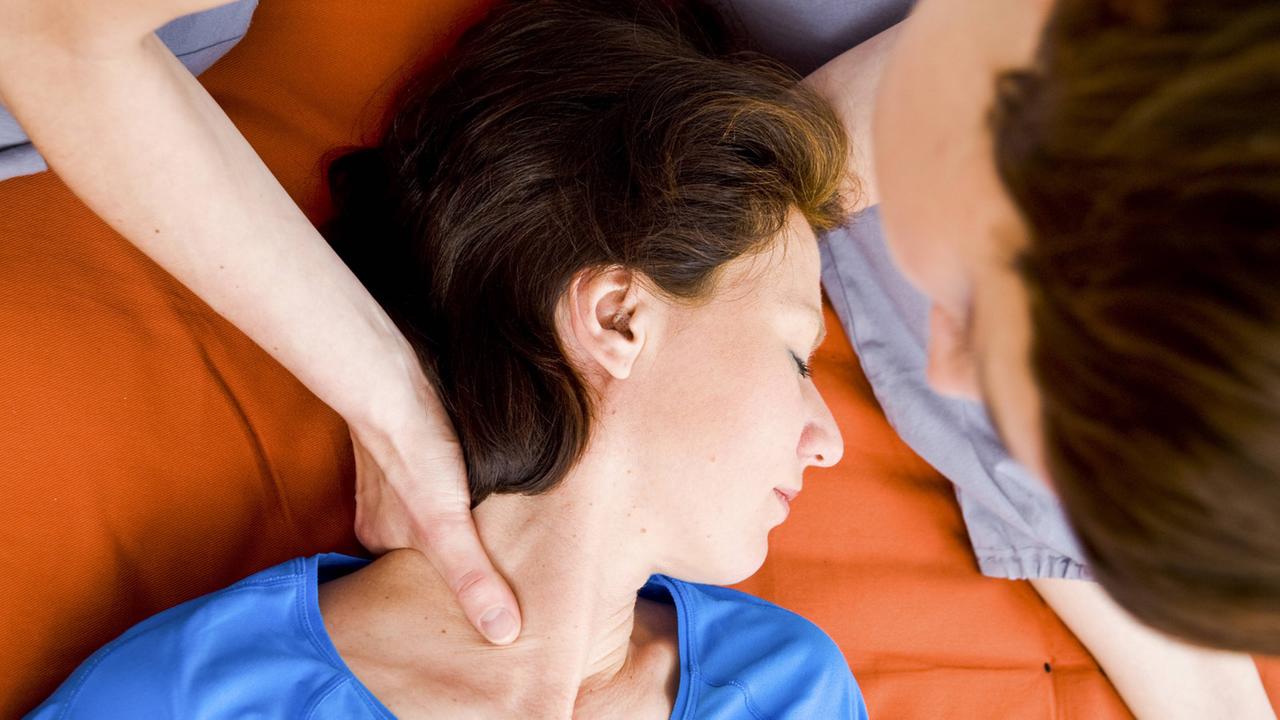 Eine Frau greift der anderen Frau während einer Körpertherapie an den Hals. Eine Frau greift der anderen Frau während einer Körpertherapie an den Hals.