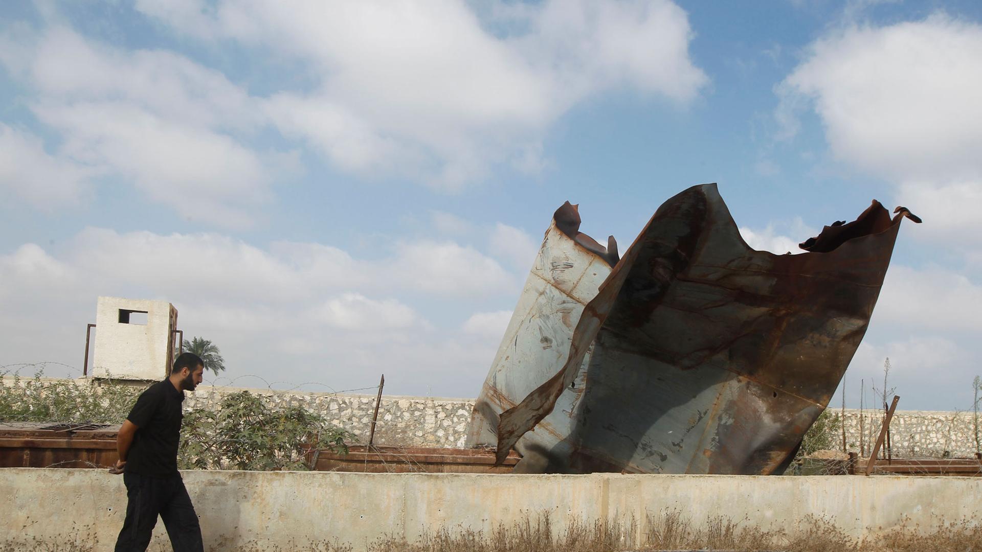 Ein Palästinenser untersucht die Schäden durch israelische Angriffe in der Stadt Rafah, während er an der Grenze zwischen Ägypten und dem Gazastreifen entlang läuft. Ein Palästinenser untersucht die Schäden durch israelische Angriffe in der Stadt Rafah, während er an der Grenze zwischen Ägypten und dem Gazastreifen entlang läuft.
