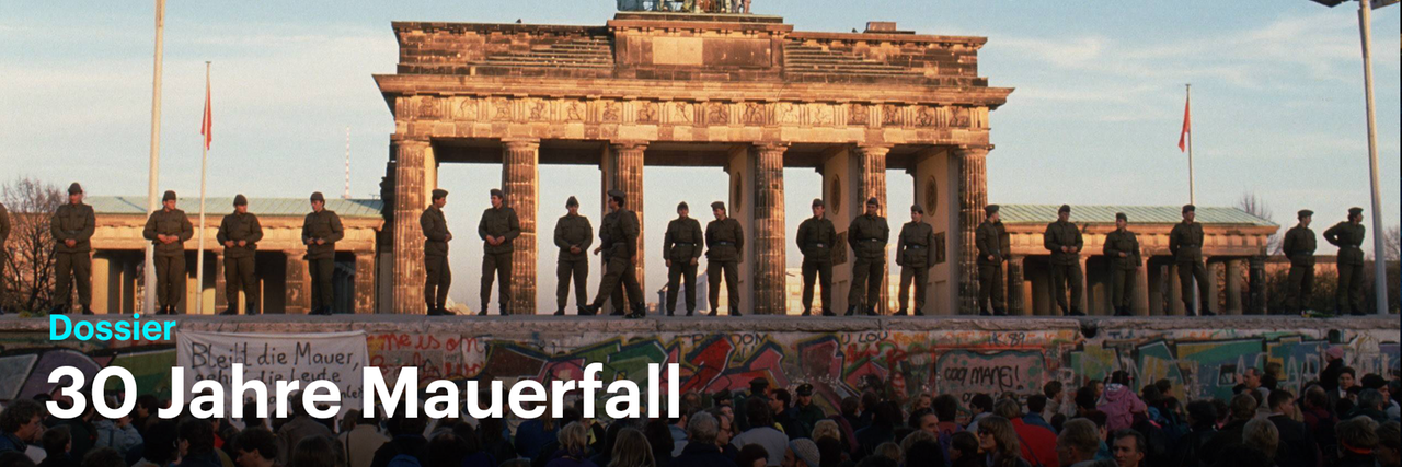Grenzpolizisten stehen auf der Mauer vor dem Brandenburger Tor. Durch ein Klick auf das Bild gelangen Sie zu unserem Dossier 30 Jahre Mauerfall.