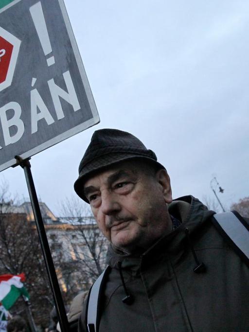 Ein Mann hält auf einer Demonstration in Budapest ein Schild mit der Aufschrift "Stop Orban".
