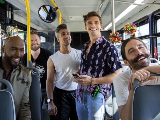 In einem Bus stehen und sitzen in fröhlicher Stimmung die 5 Darsteller der Netflix-Reality-Show "Queer Eye".