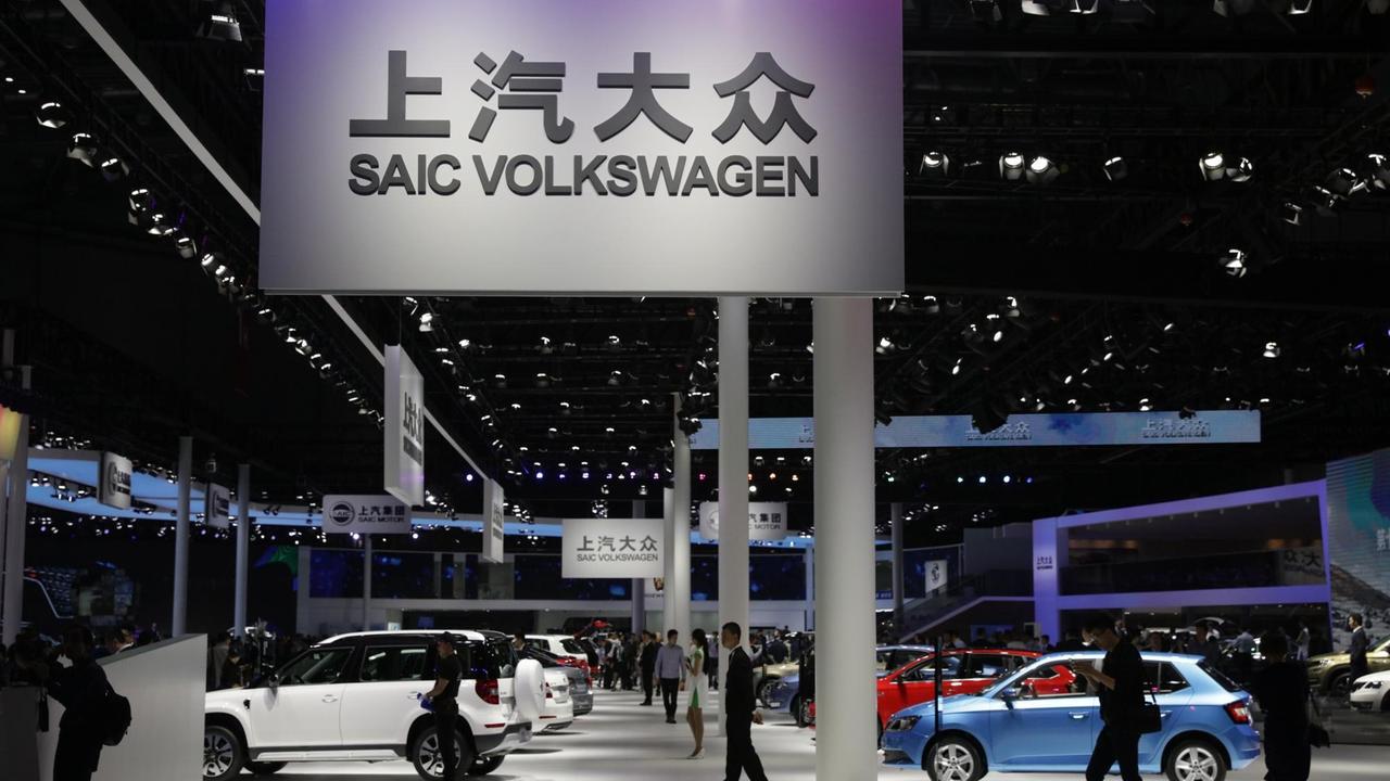 Autos stehen in einer Halle auf der Internationalen Automobil-Ausstellung. Menschen gehen unter einem Schild mit der Aufschrift "Volkswagen" lang. Autos stehen in einer Halle auf der Internationalen Automobil-Ausstellung. Menschen gehen unter einem Schild mit der Aufschrift "Volkswagen" lang.