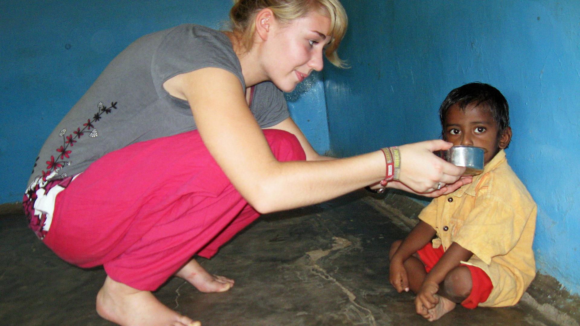 Dieses Pressefoto zeigt die 19-jährige Sira Müller aus der Nähe von Bremen, die 2008 einem Kind in Südindien in einem Kindergarten etwas zu trinken gibt. Als eine der ersten engagierte sie sich freiwillig für das Programm "weltwärts".