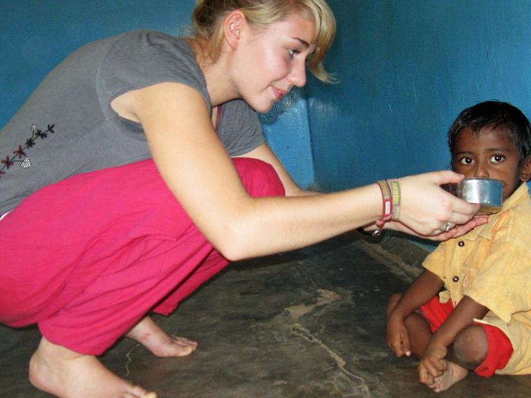 Dieses Pressefoto zeigt die 19-jährige Sira Müller aus der Nähe von Bremen, die 2008 einem Kind in Südindien in einem Kindergarten etwas zu trinken gibt. Als eine der ersten engagierte sie sich freiwillig für das Programm "weltwärts".