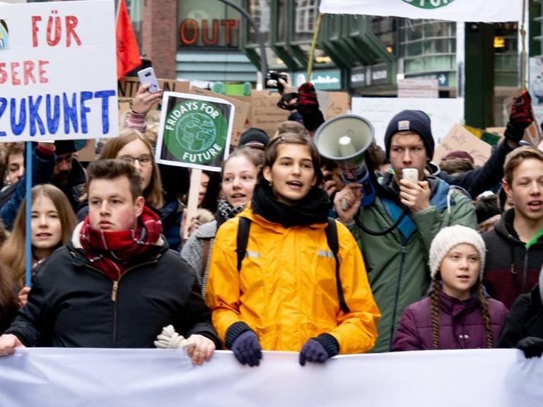 Zahlreiche Demonstrantinnen und Demonstranten gehen durch die Straßen und halten ein Transparent vor sich.