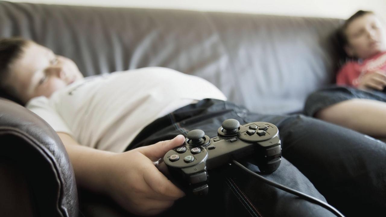 Zwei schlafende Jungs mit Game-Controllern schlafen auf einem Sofa. Zwei schlafende Jungs mit Game-Controllern schlafen auf einem Sofa.