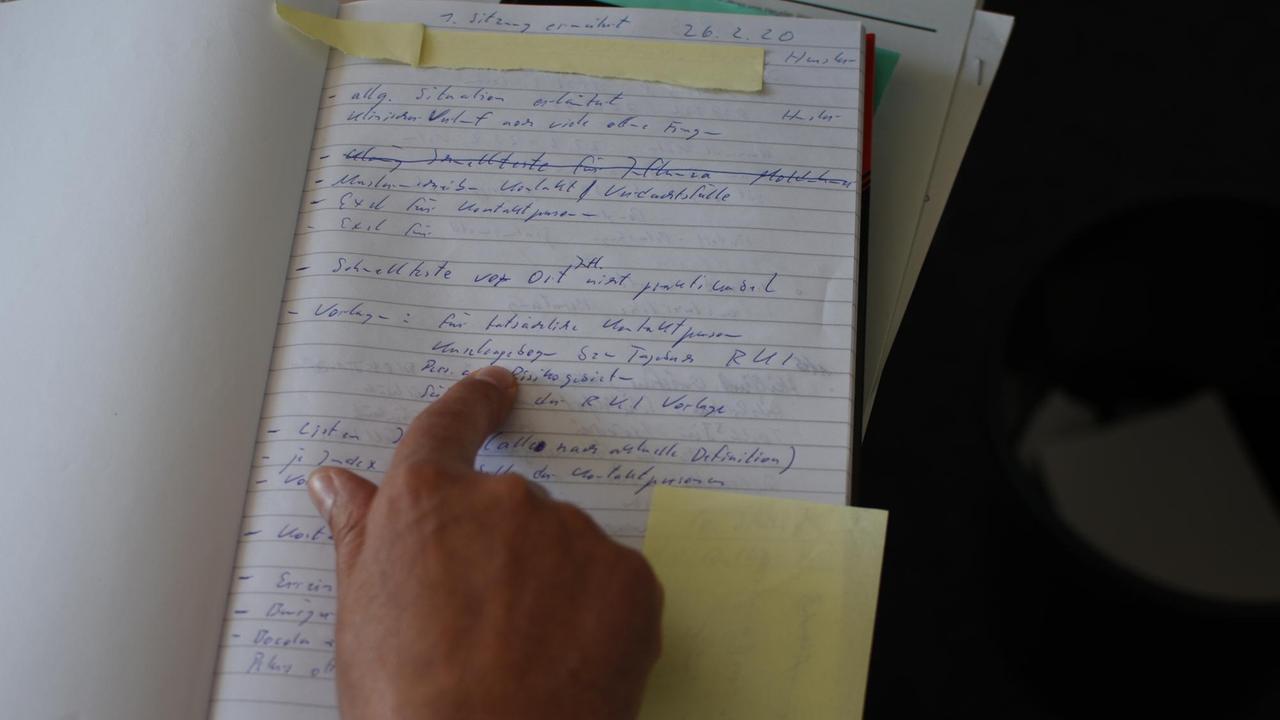 Die Hand von Jörg Heusler, Leiter des Gesundheitsamts Vorpommern-Rügen, deutet auf die Einträge in einer Seite seines Corona-Tagebuchs 
