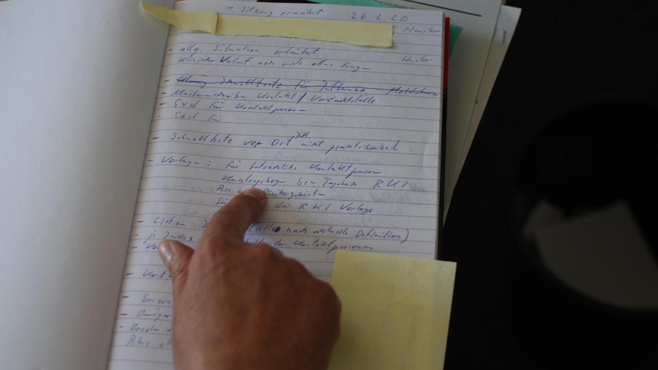 Die Hand von Jörg Heusler, Leiter des Gesundheitsamts Vorpommern-Rügen, deutet auf die Einträge in einer Seite seines Corona-Tagebuchs Die Hand von Jörg Heusler, Leiter des Gesundheitsamts Vorpommern-Rügen, deutet auf die Einträge in einer Seite seines Corona-Tagebuchs