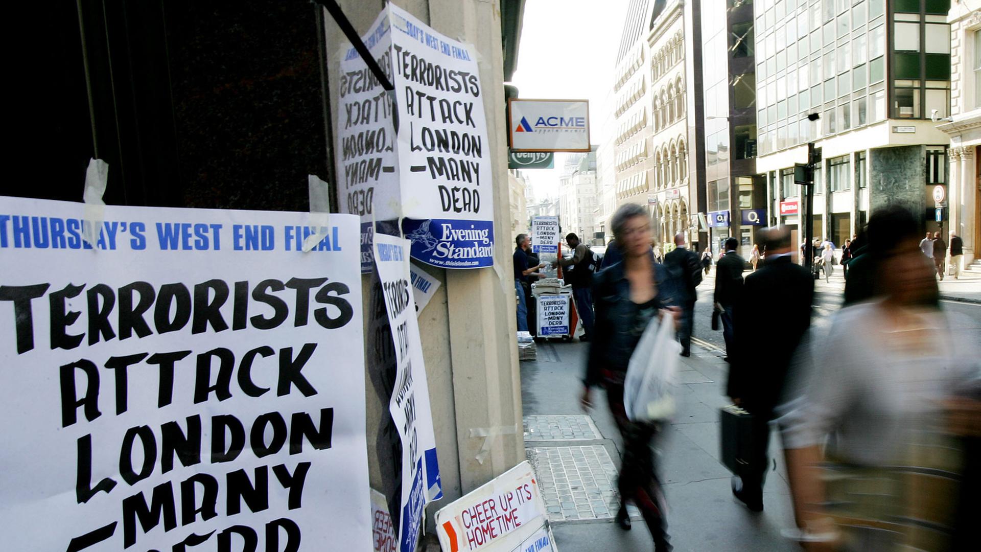 Fußgänger laufen am 07.07.2005 an einem Zeitungsstand vorbei, an dem die Terroranschläge auf die U-Bahn in London angekündigt werden.