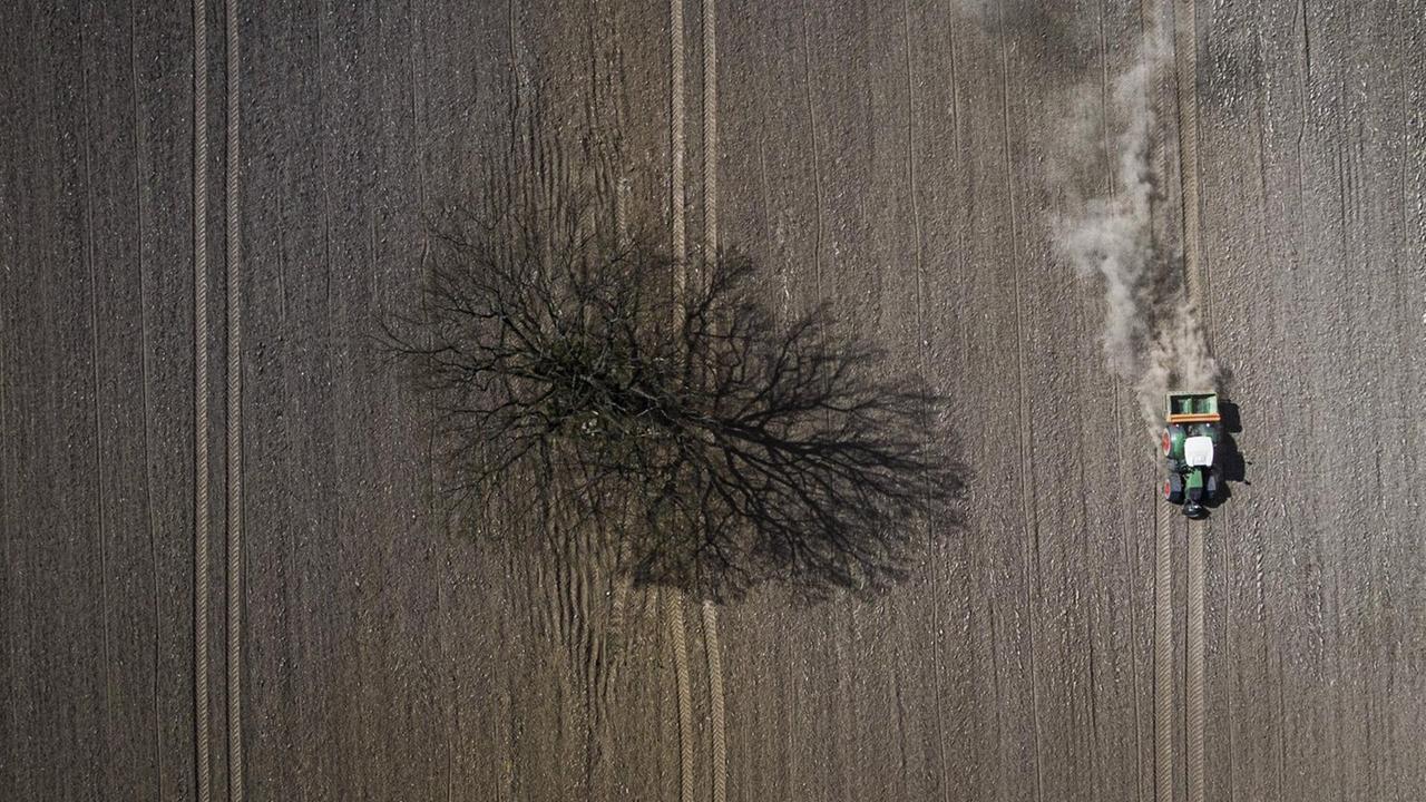 Aufsicht auf ein trockenes Feld, ein Trecker bearbeitet den Boden. Aufsicht auf ein trockenes Feld, ein Trecker bearbeitet den Boden.